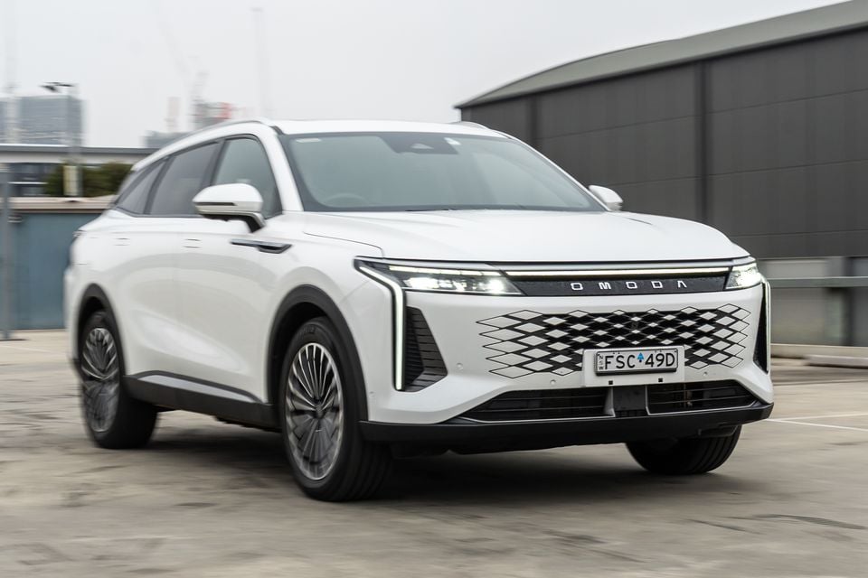 A white Omoda 9 SUV seen from the front three-quarter angle in an urban setting