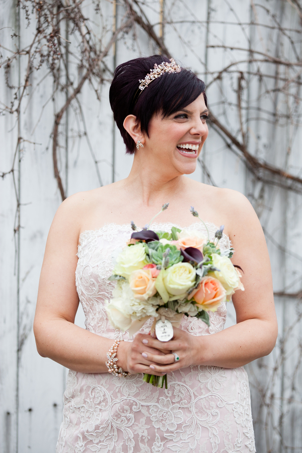 Cream and peach rose bouquet with deep-purple mini calla lilies, lavender sprigs, and an engraved charm