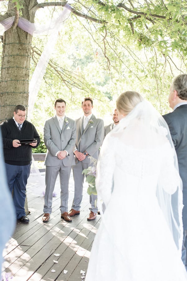 Bride walking down the aisle with her father as the groom smiles at a creamery wedding