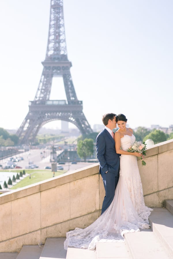 Bride in a strapless lace gown with a cathedral train beside her groom at a Paris castle