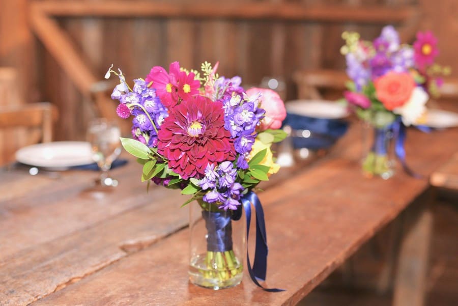 Colorful loose wildflower bouquets in glass vases on wood