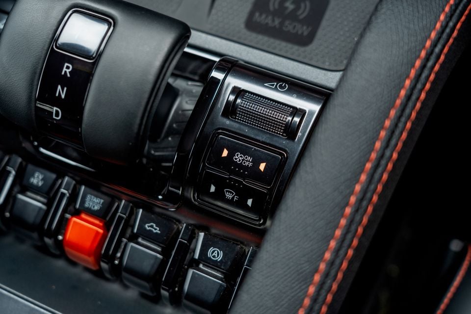 Centre console controls in the 2026 BYD Shark 6, showing the gear selector, volume roller, fan and demister switches, a red start button and the 50W wireless charging pad