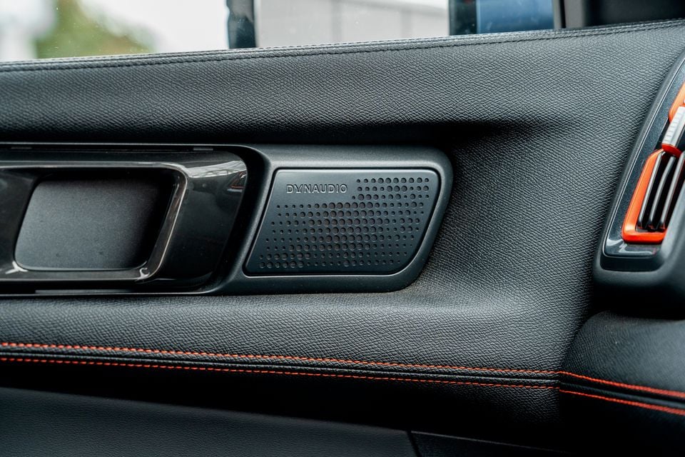 Dynaudio speaker grille and door handle on the black leather door trim of a 2026 BYD Shark 6 with orange contrast stitching