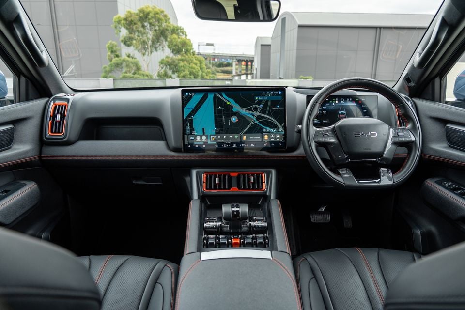 Dashboard of the 2026 BYD Shark 6 Premium ute, showing the steering wheel, central touchscreen with navigation map, digital driver display and black leather seats with orange stitching