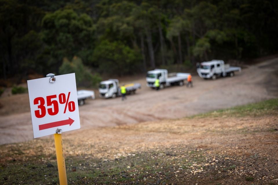 A steep gravel incline marked with a 35% gradient sign, with several Isuzu NMS flatbed trucks parked near the top, used for a truck testing demonstration.