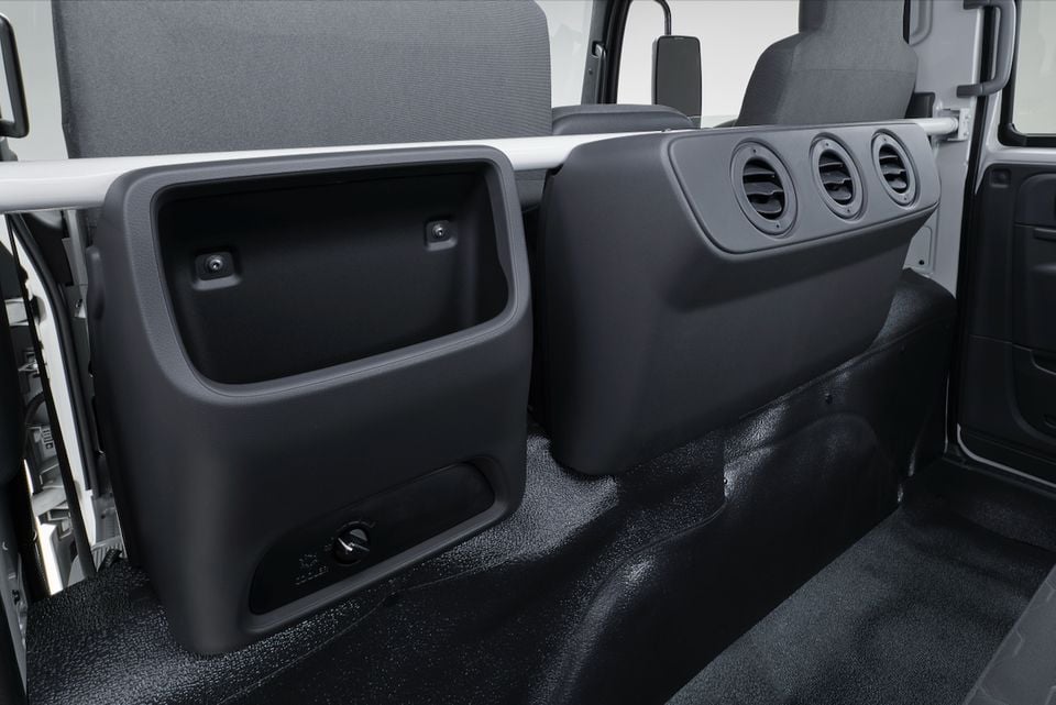 The rear cabin of a 2026 Isuzu NMS truck showing storage bins, air vents and rear seating behind the front seats.
