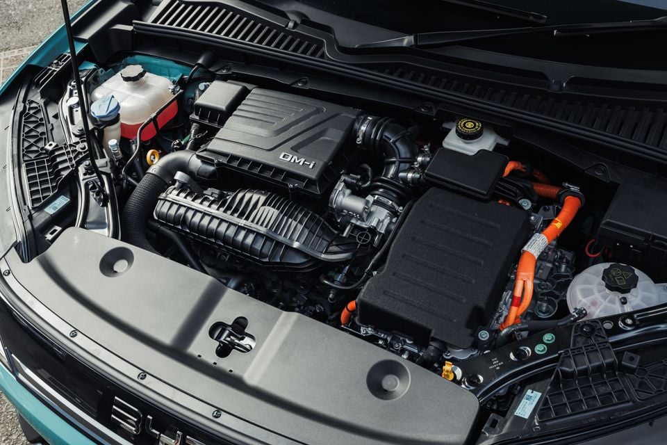 Close-up view of the DM-i hybrid engine bay in a 2027 BYD Atto 2, showing the engine, orange high-voltage cables and fluid reservoirs