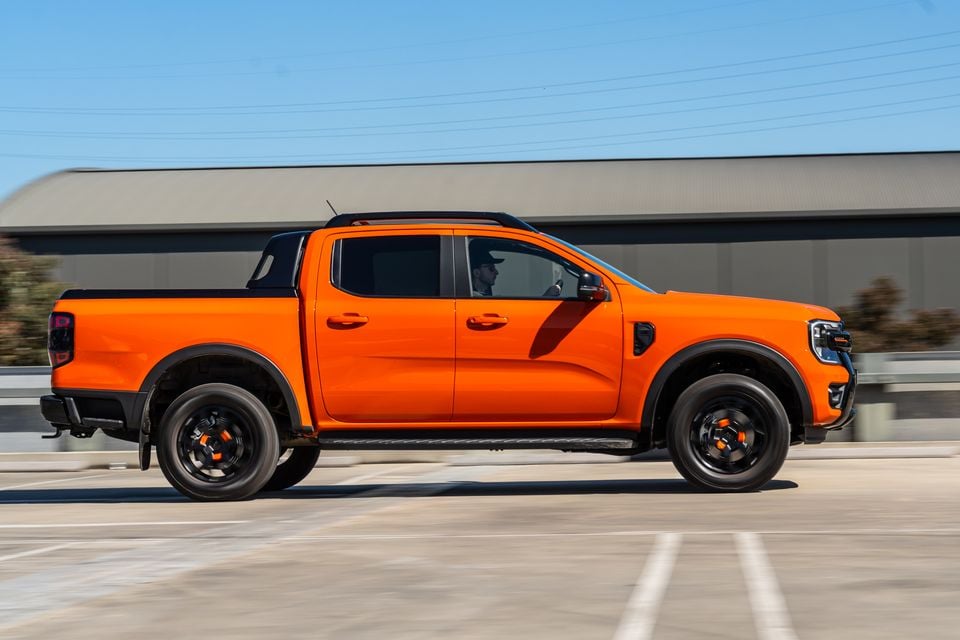 An orange Ford Ranger Wildtrak dual-cab ute seen from the side while driving on a road