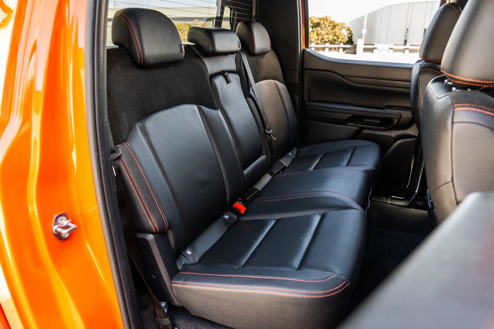 Rear seat interior of a Ford Ranger Wildtrak dual-cab ute, showing black leather upholstery with orange contrast stitching