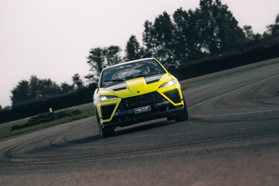 A yellow 2027 Lamborghini Urus SE Performante SUV driving towards the camera on a race track