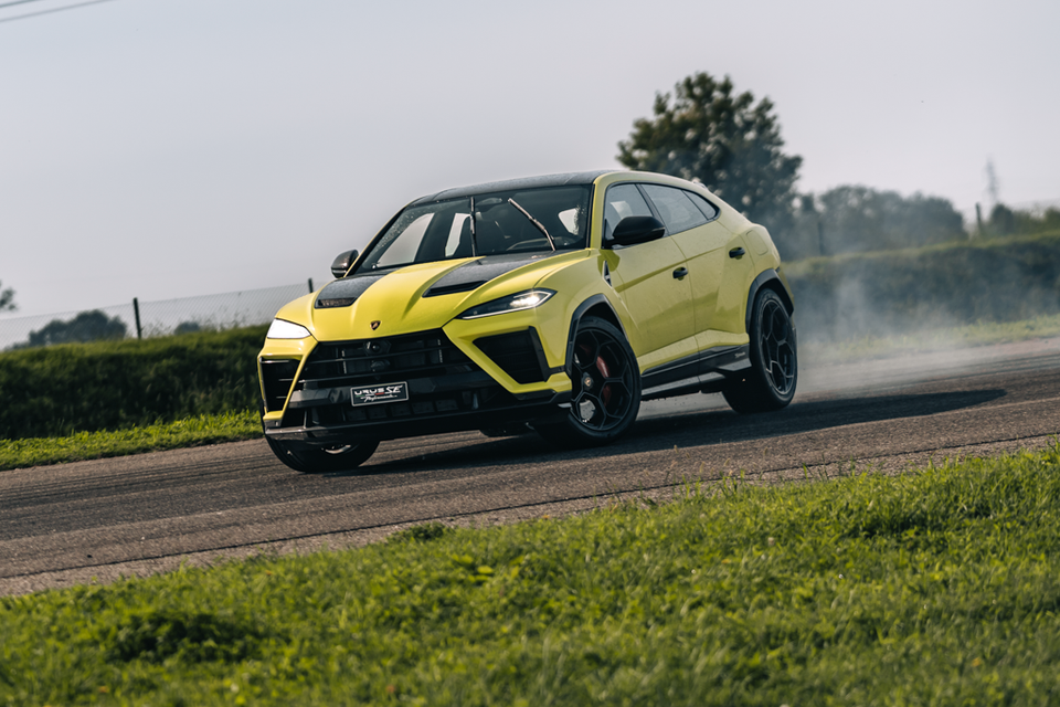 A yellow 2027 Lamborghini Urus SE Performante SUV drifting on a racetrack with tyre smoke, seen from the front left