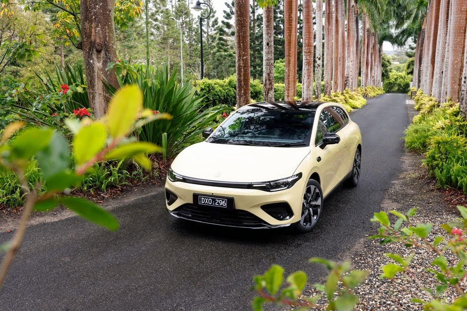 A cream 2027 Leapmotor B05 hatchback parked on a tree-lined garden driveway, seen from the front.