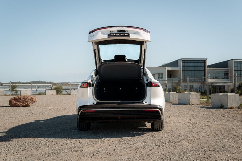 A white 2027 Mazda 6e Atenza liftback shown from the rear with its tailgate open, revealing the boot