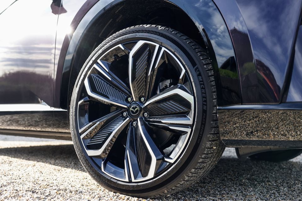Close-up of the alloy wheel on a dark blue 2027 Mazda CX-6e electric SUV, with a Michelin tyre and Mazda badge visible