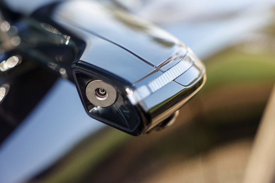 A close-up view of a side mirror camera on a 2027 Mazda CX-6e, replacing a traditional wing mirror