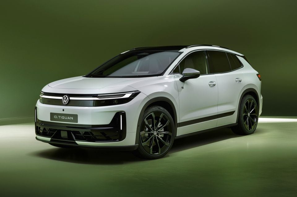 A white 2027 Volkswagen ID. Tiguan electric SUV with black wheels, seen from the front left in a green studio