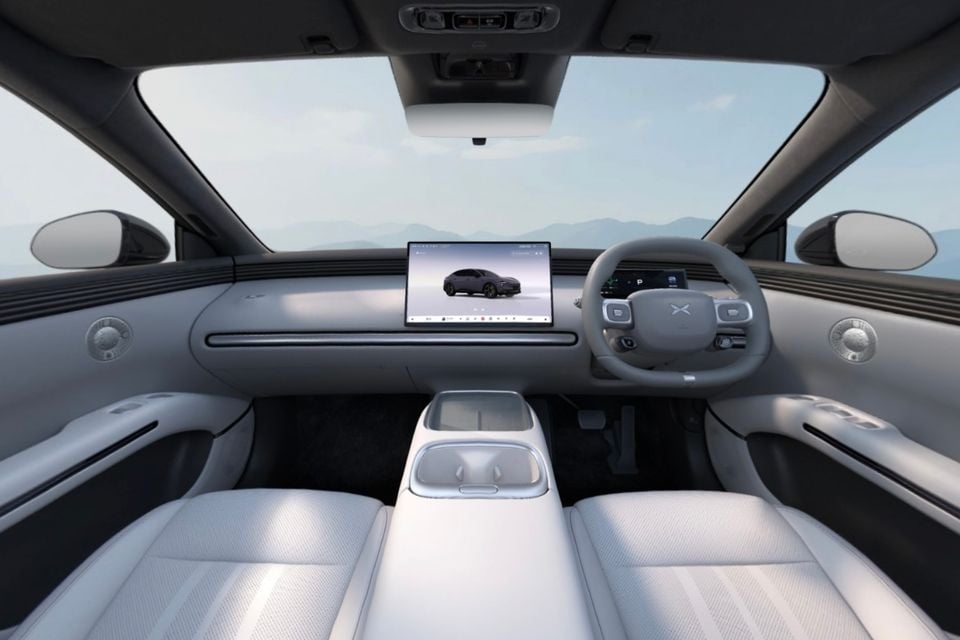 The light grey interior of a Xpeng L03 showing the dashboard, steering wheel, centre touchscreen and front seats.