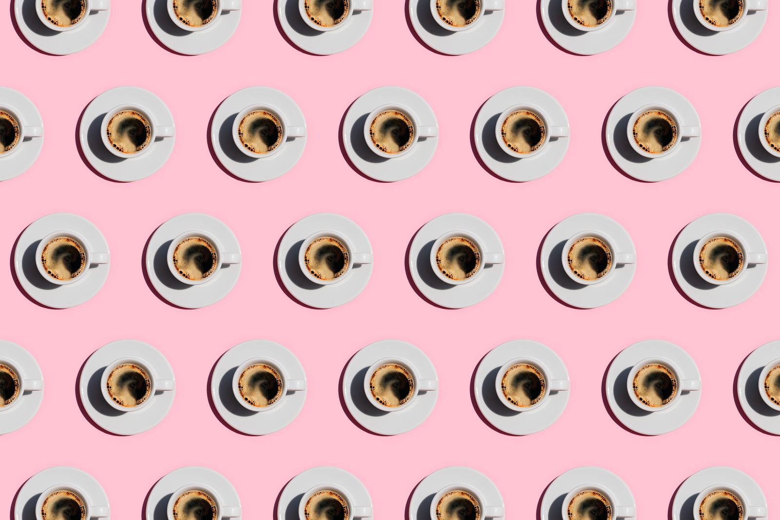 Pattern made of cup of fresh coffee on pastel pink background.