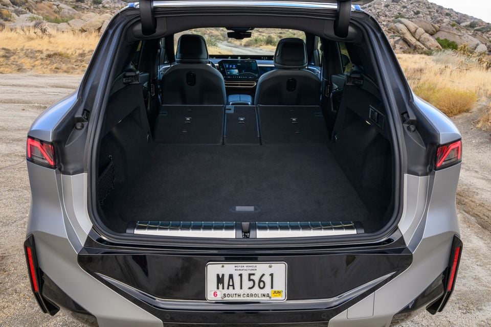 Open boot of a silver BMW X5 xDrive40 SUV with the rear seats folded flat, seen from behind in a rocky desert setting
