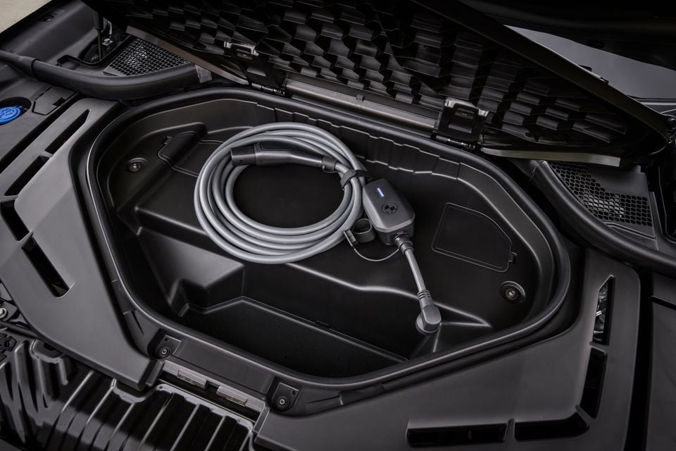 A BMW portable charging cable coiled inside a storage compartment under the open bonnet