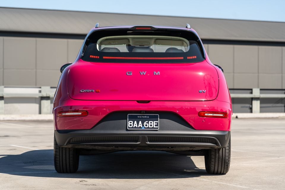A pink GWM Ora 5 electric SUV parked on a rooftop car park, seen from directly behind