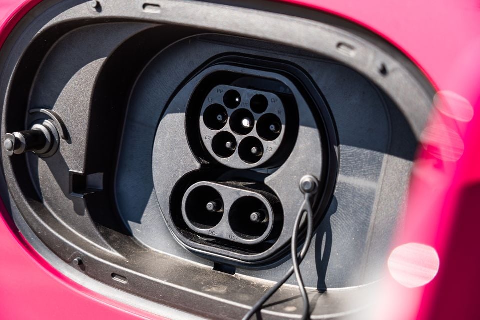 Close-up of the open CCS2 charging port on a pink GWM Ora 5, showing the Type 2 AC pins above the two DC fast-charging pins