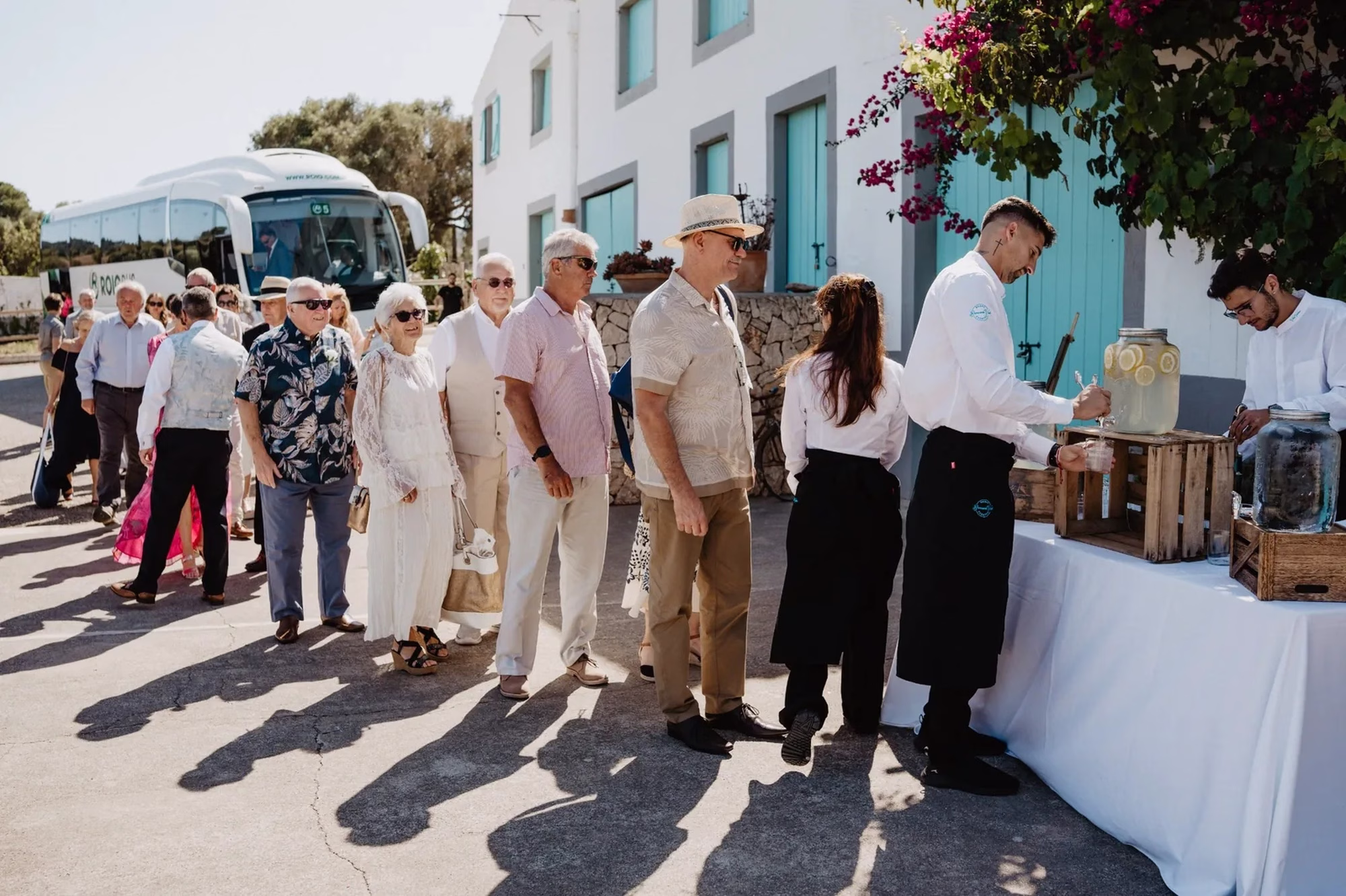 happiness mode photography 03 landscape - Getting Married in Mallorca From The UK: What You Need To Know Before You Book Anything Elderly wedding guests lined up as they exit a bus and receive a welcome drink in Mallorca. Dybiec Weddings.