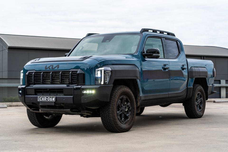 A teal Kia Tasman X-Pro dual-cab ute seen from the front-side angle in a car park