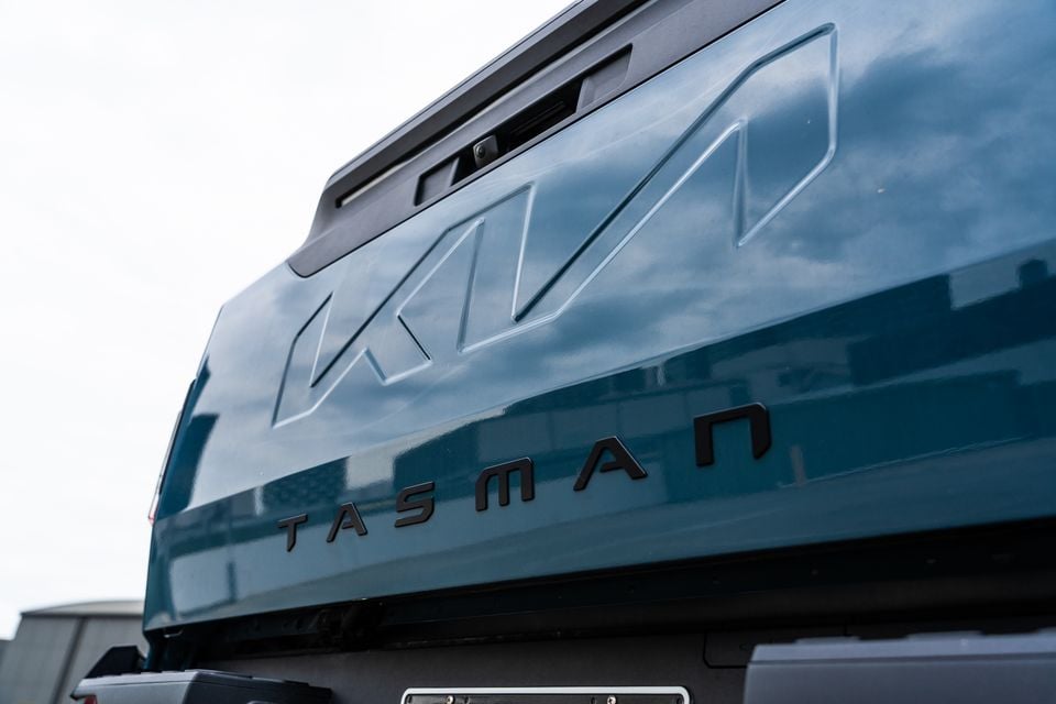 Close-up of the tailgate on a Kia Tasman ute in teal, showing the embossed Kia logo and Tasman lettering