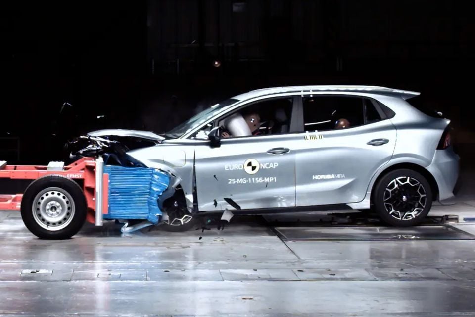 A silver MG4 EV Urban hatchback after a Euro NCAP frontal offset crash test, its crumpled front pressed against a test barrier trolley