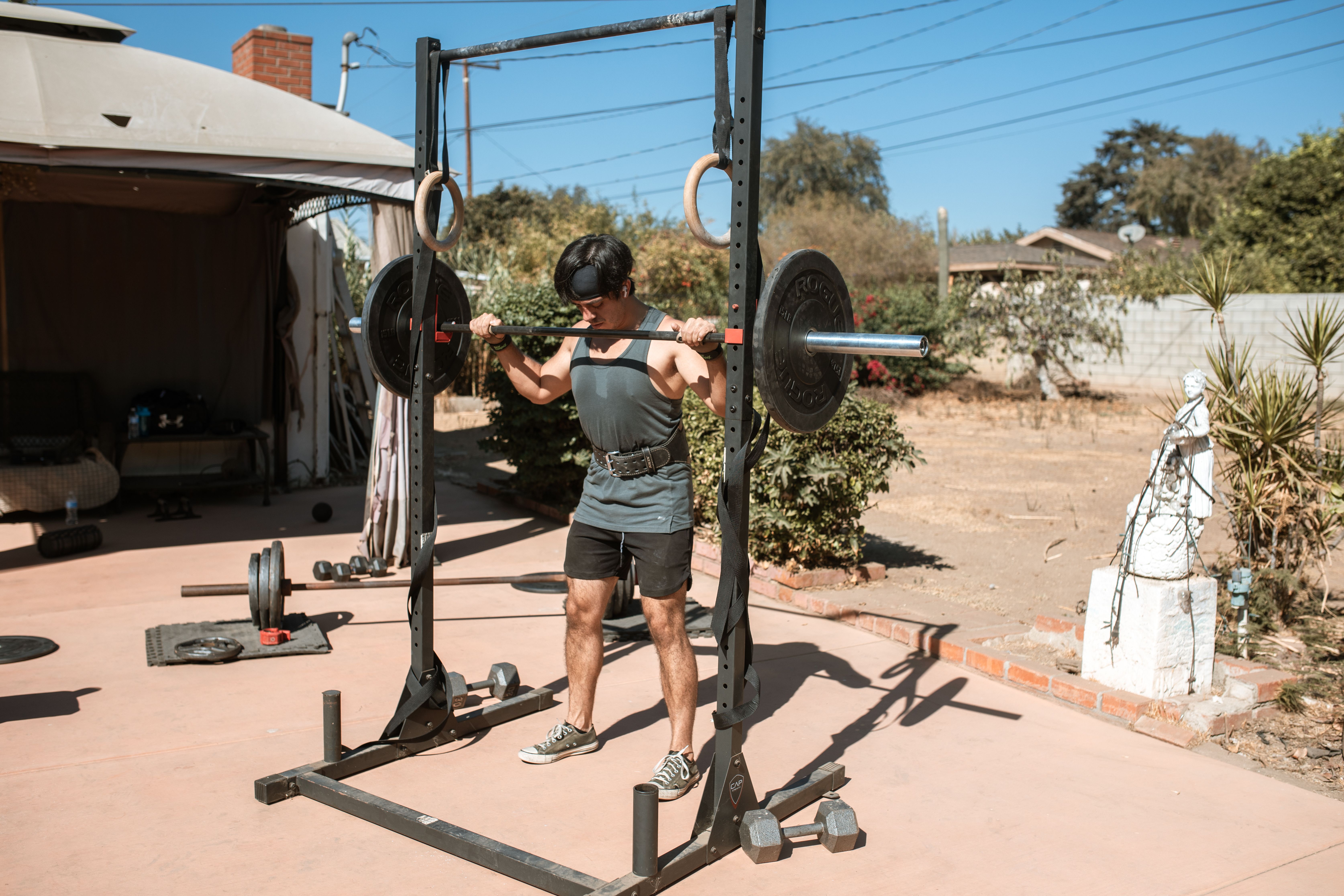 Athlete performing a barbell squat in an outdoor workout space.