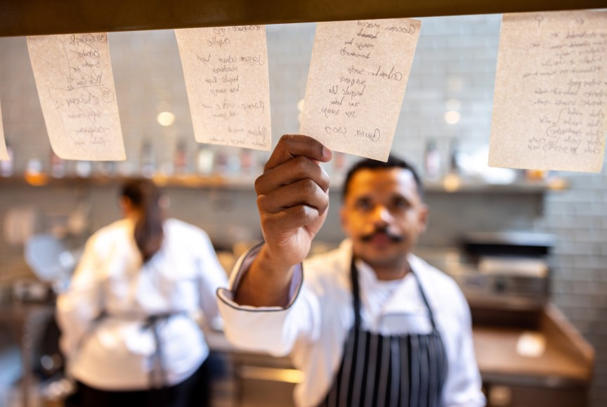 A restaurant worker grabbing an order ticket.