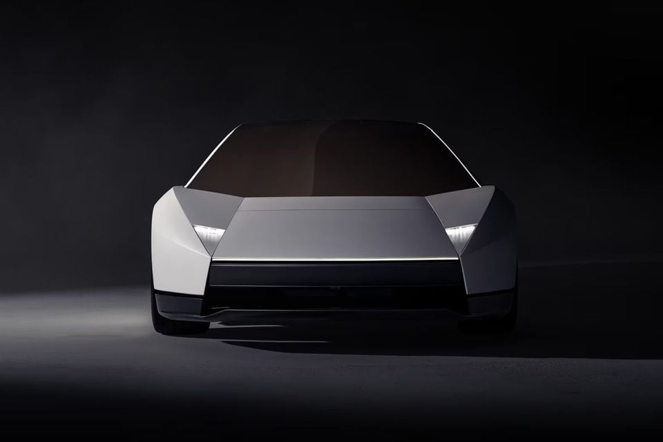 A silver wedge-shaped sports car with slim LED headlights, seen from the front in a dark studio