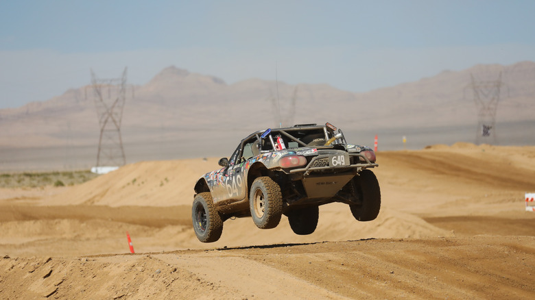 The back end of Buddy the off-roading Miata as it lands on a sandy hill on a desert track